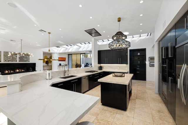 kitchen featuring kitchen peninsula, stainless steel appliances, sink, decorative light fixtures, and a large island