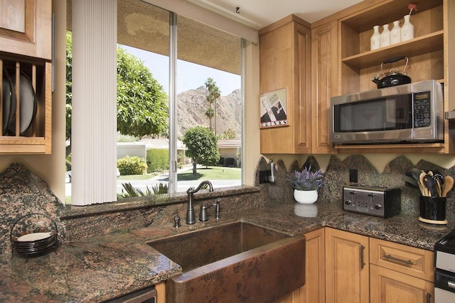 kitchen with a mountain view, dark stone countertops, and sink