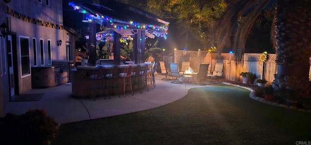 patio at night featuring exterior bar and a fire pit