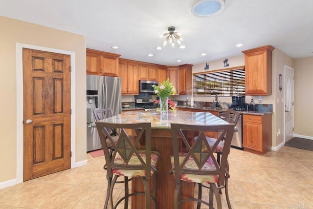 14429 Springvale St, Poway, CA 92064 - kitchen featuring appliances with stainless steel finishes, light stone counters, baseboards, and a breakfast bar