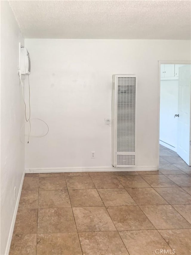 spare room with a wall mounted air conditioner and a textured ceiling