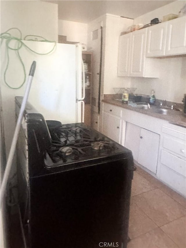 kitchen featuring white cabinetry, sink, black electric range oven, and light tile patterned floors