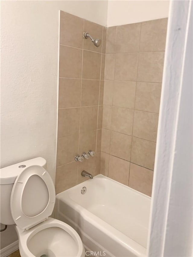 bathroom featuring tiled shower / bath combo and toilet