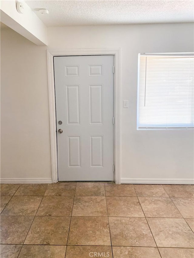 doorway to outside with tile patterned flooring and a textured ceiling