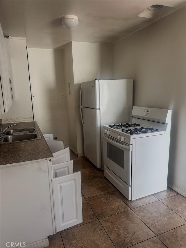 kitchen featuring dark tile patterned floors, white appliances, sink, and white cabinetry