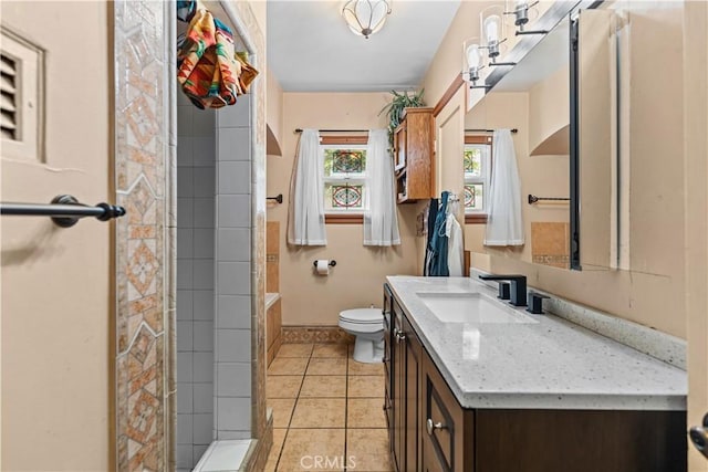 bathroom featuring tiled shower, vanity, tile patterned floors, and toilet