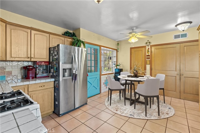 kitchen with tasteful backsplash, stainless steel fridge, tile counters, and ceiling fan