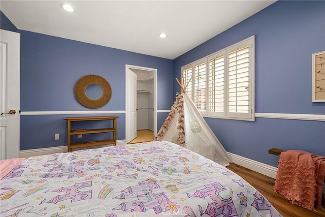 bedroom with a spacious closet, a closet, and wood-type flooring