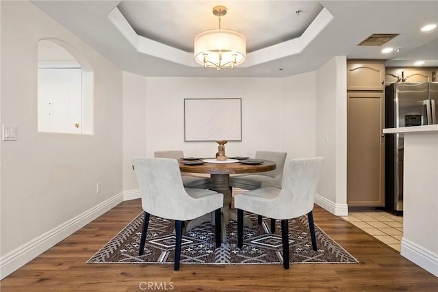 dining space featuring light hardwood / wood-style floors and a tray ceiling