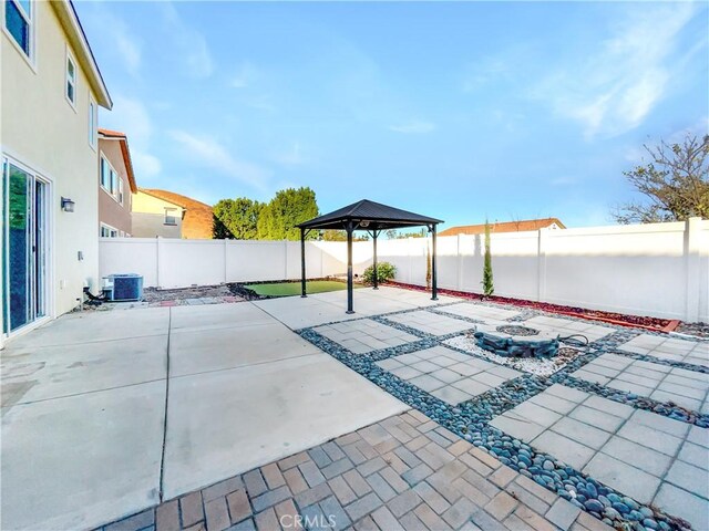 view of patio featuring a gazebo, cooling unit, and an outdoor fire pit