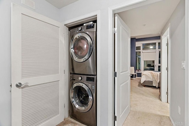 laundry room featuring light colored carpet and stacked washer / dryer