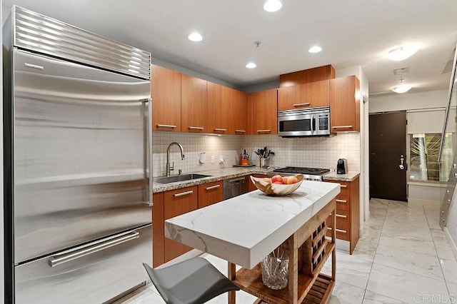 kitchen with appliances with stainless steel finishes, backsplash, a kitchen island, and sink