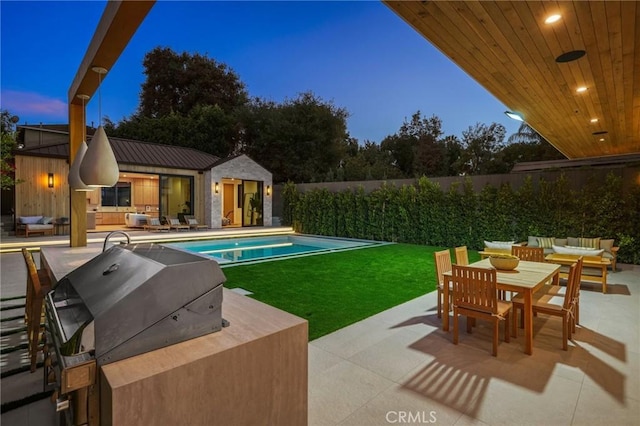 pool at dusk featuring outdoor lounge area, a patio area, and a yard