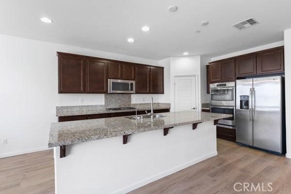 kitchen featuring appliances with stainless steel finishes, sink, a breakfast bar area, backsplash, and a kitchen island with sink