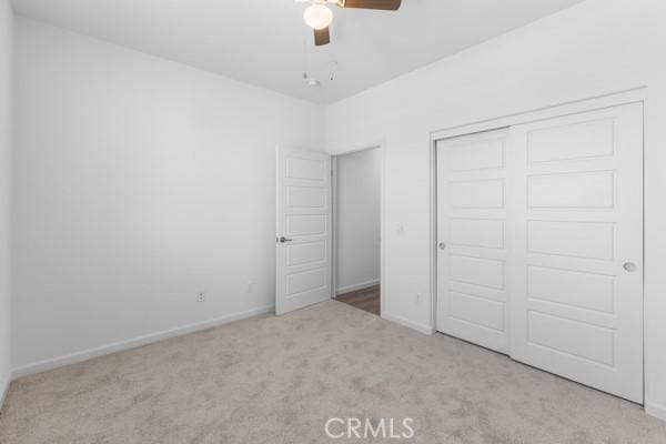 unfurnished bedroom with ceiling fan, light colored carpet, and a closet