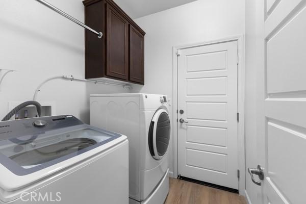 laundry area with dark wood-type flooring, cabinets, and separate washer and dryer