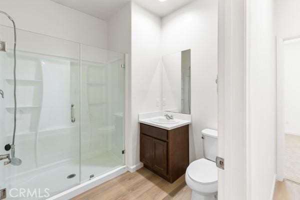 bathroom featuring hardwood / wood-style flooring, vanity, toilet, and a shower with shower door