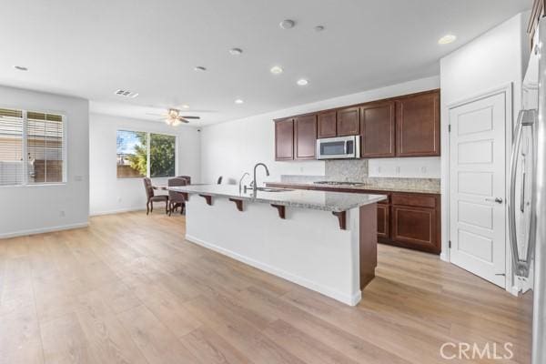 kitchen with tasteful backsplash, sink, a breakfast bar area, a kitchen island with sink, and stainless steel appliances