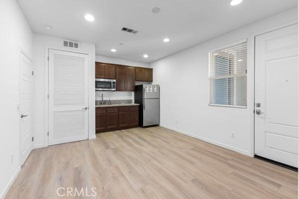 kitchen featuring appliances with stainless steel finishes, light hardwood / wood-style floors, and dark brown cabinets