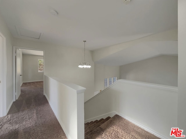 corridor with a chandelier, dark carpet, and vaulted ceiling