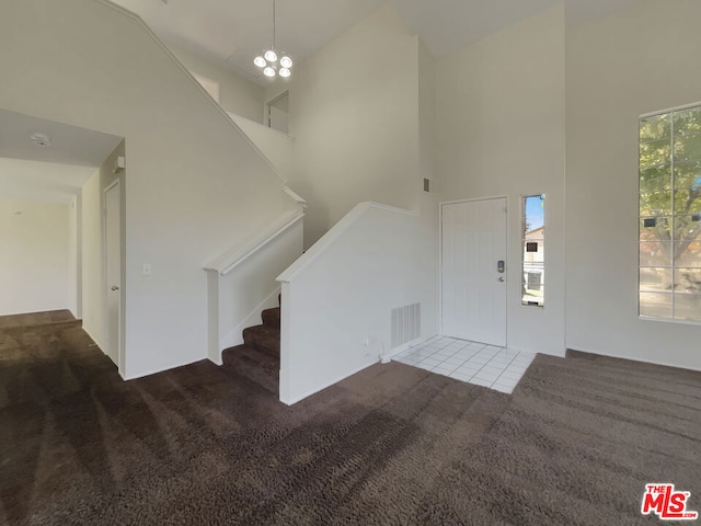 foyer with carpet floors, an inviting chandelier, and high vaulted ceiling