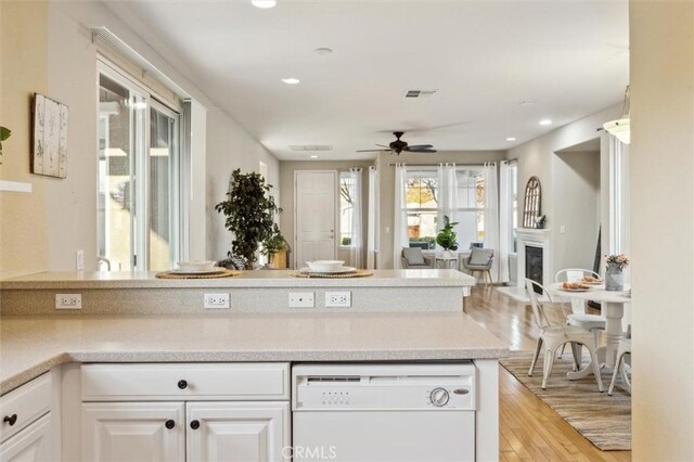 kitchen featuring light wood-type flooring, ceiling fan, dishwasher, and white cabinets