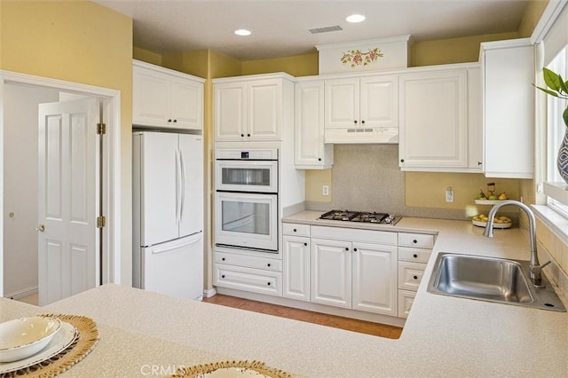 kitchen with white cabinetry, sink, white appliances, and backsplash