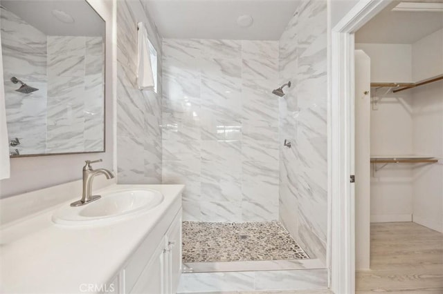 bathroom featuring hardwood / wood-style flooring, tiled shower, and vanity