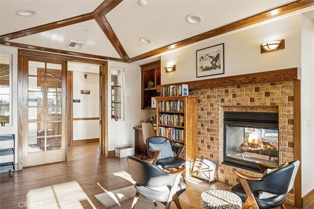 sitting room featuring lofted ceiling with beams, dark hardwood / wood-style flooring, and a brick fireplace