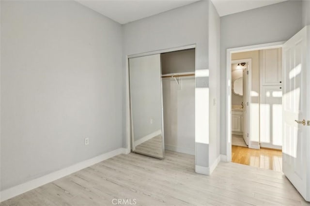 unfurnished bedroom with light wood-type flooring and a closet