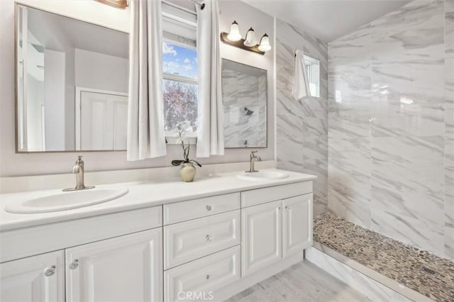 bathroom with tiled shower and vanity