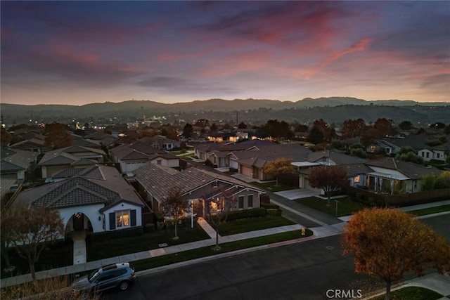 aerial view at dusk featuring a mountain view and a residential view