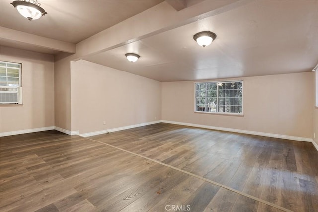 empty room with beam ceiling, hardwood / wood-style flooring, plenty of natural light, and cooling unit