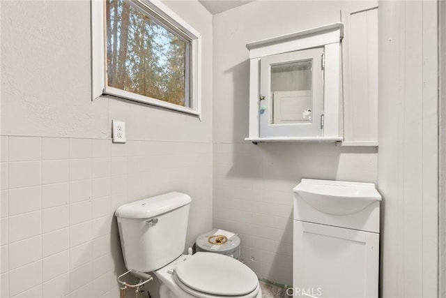 bathroom with vanity, toilet, and tile walls