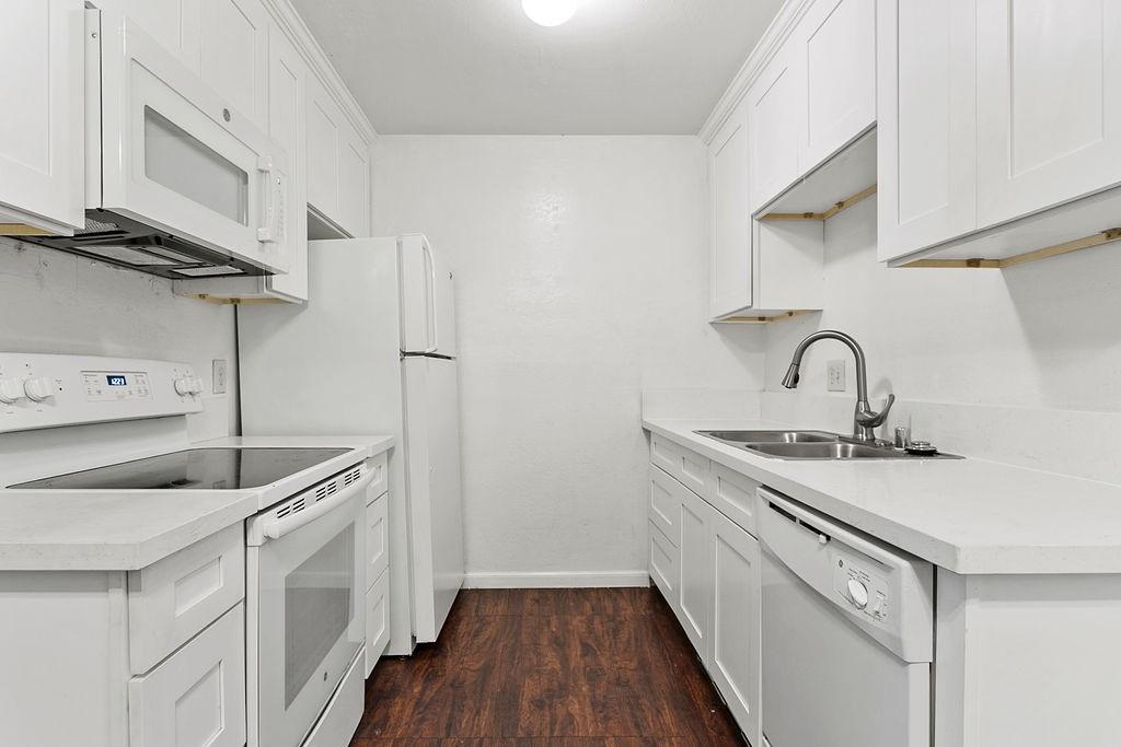 kitchen featuring white cabinetry, dark wood-type flooring, and white appliances