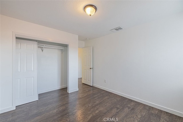 unfurnished bedroom featuring a closet and dark wood-type flooring