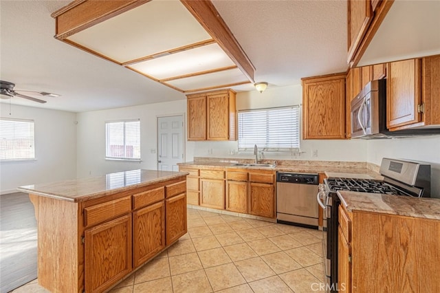 kitchen with sink, ceiling fan, light tile patterned floors, appliances with stainless steel finishes, and a kitchen island