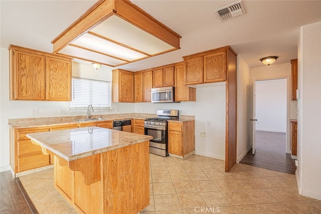 kitchen with a center island, light tile patterned flooring, stainless steel appliances, and sink