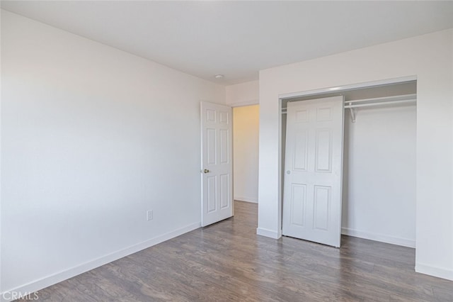 unfurnished bedroom with dark wood-type flooring and a closet