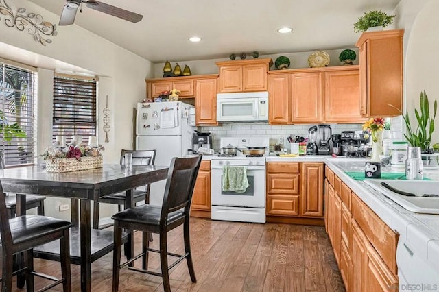 kitchen with ceiling fan, sink, tasteful backsplash, wood-type flooring, and white appliances