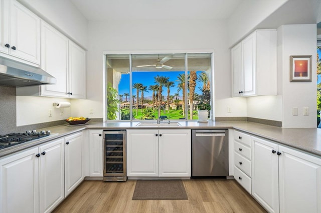 kitchen featuring sink, light hardwood / wood-style flooring, appliances with stainless steel finishes, white cabinetry, and beverage cooler