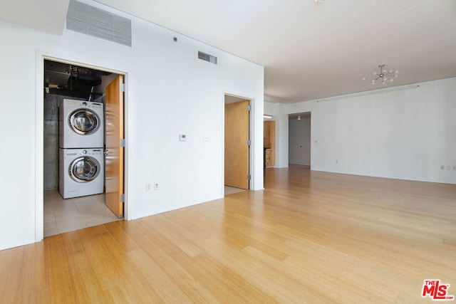 empty room with stacked washer and dryer and light hardwood / wood-style floors