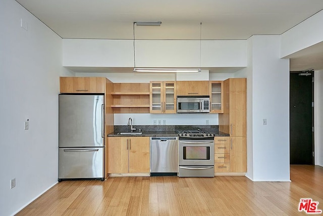 kitchen with sink, appliances with stainless steel finishes, and light hardwood / wood-style flooring