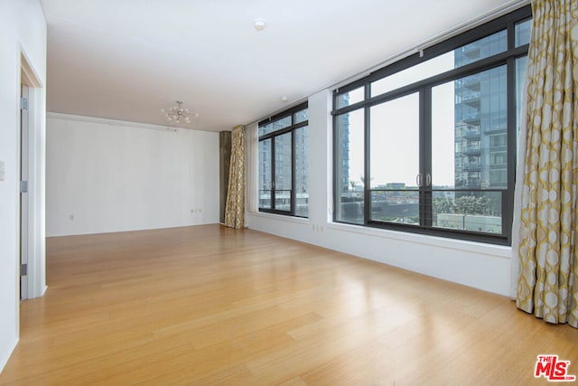 empty room with a chandelier and light wood-type flooring