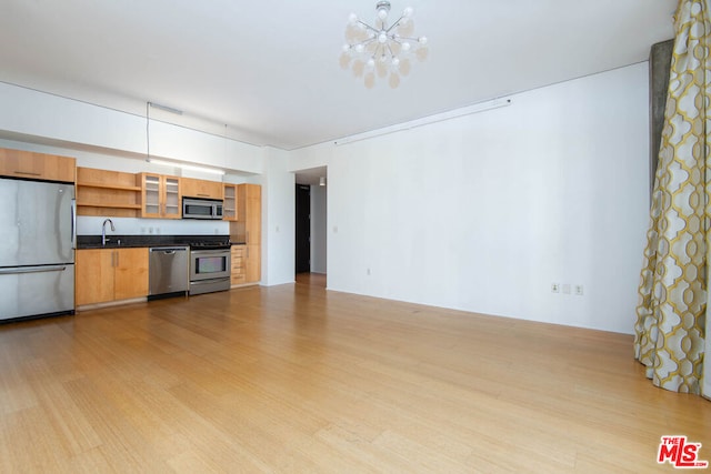 kitchen featuring sink, hanging light fixtures, stainless steel appliances, an inviting chandelier, and light hardwood / wood-style floors