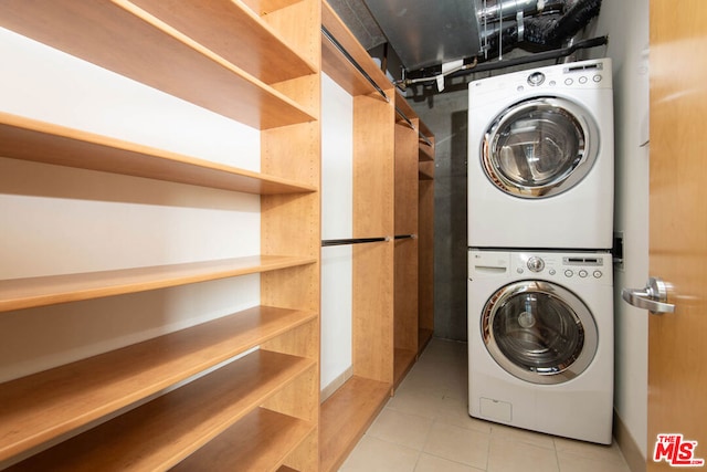 laundry room with stacked washer / dryer and light tile patterned floors