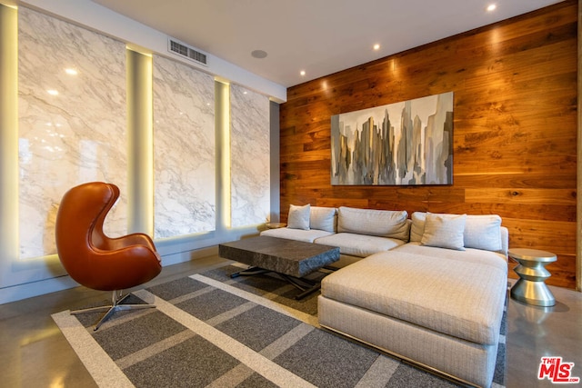 living room with concrete flooring and wooden walls