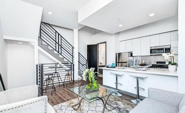 kitchen with kitchen peninsula, stainless steel appliances, dark wood-type flooring, sink, and white cabinetry