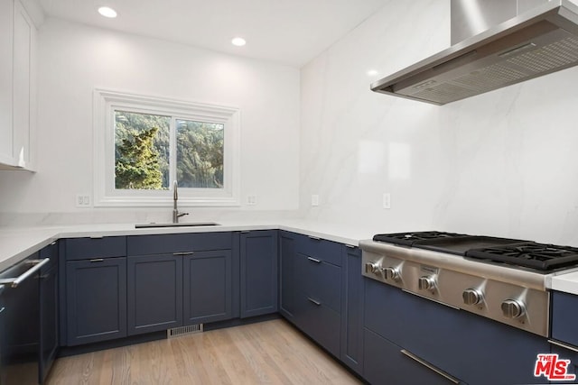 kitchen with sink, stainless steel appliances, wall chimney range hood, and light wood-type flooring