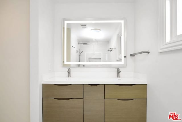 bathroom with a tile shower and vanity